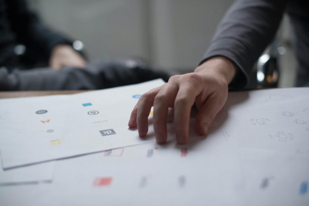 A close-up shot of a hand reviewing various logo designs on paper, ideal for business concepts.